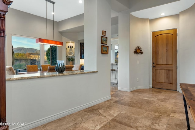 kitchen featuring light stone counters, a mountain view, decorative light fixtures, and a high ceiling