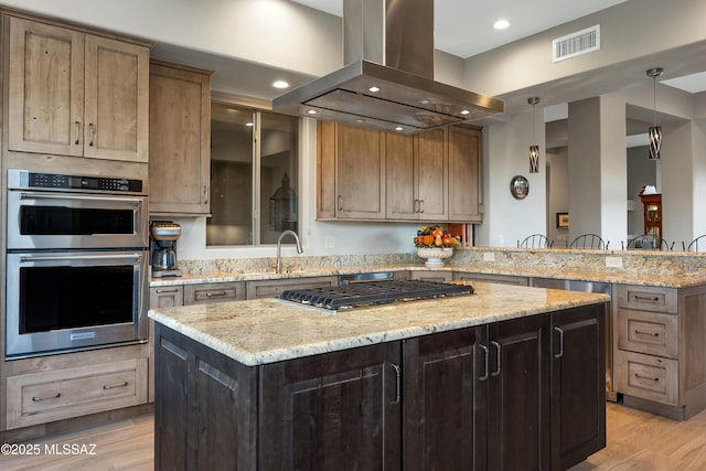 kitchen with island range hood, light stone countertops, appliances with stainless steel finishes, and a kitchen island