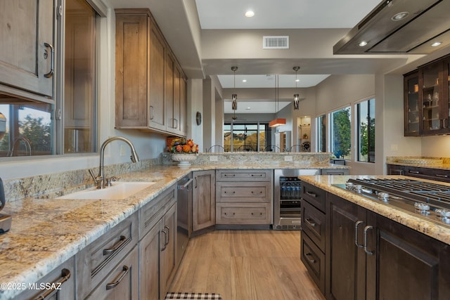 kitchen featuring sink, light hardwood / wood-style floors, kitchen peninsula, stainless steel gas cooktop, and beverage cooler