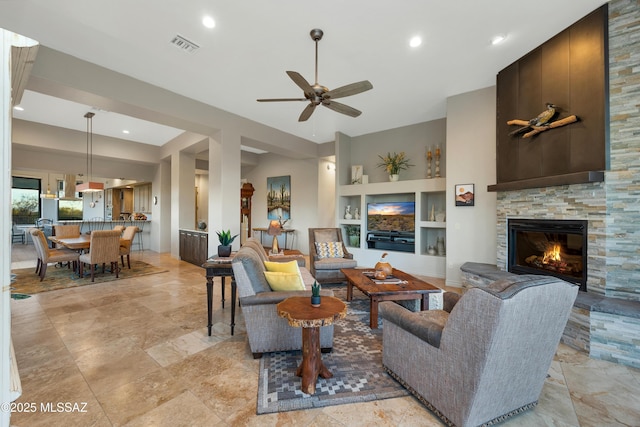 living room with ceiling fan, a fireplace, and built in shelves