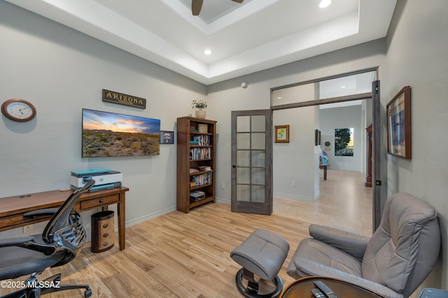 office area with a raised ceiling, ceiling fan, french doors, and light hardwood / wood-style flooring