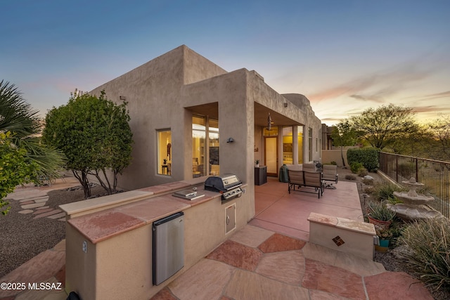 patio terrace at dusk featuring area for grilling