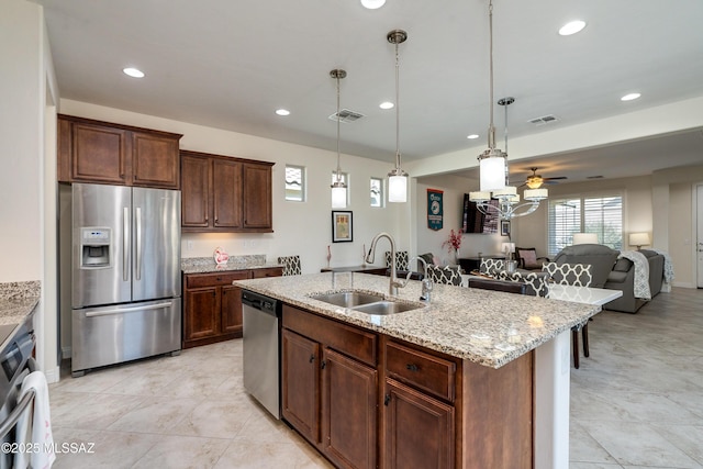 kitchen featuring appliances with stainless steel finishes, sink, an island with sink, and hanging light fixtures