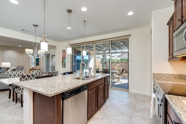 kitchen with a breakfast bar, sink, a center island with sink, appliances with stainless steel finishes, and pendant lighting