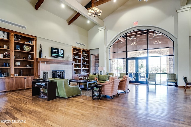 living room featuring an inviting chandelier, high vaulted ceiling, wood-type flooring, a brick fireplace, and beamed ceiling