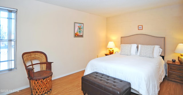 bedroom featuring hardwood / wood-style flooring, brick wall, and multiple windows