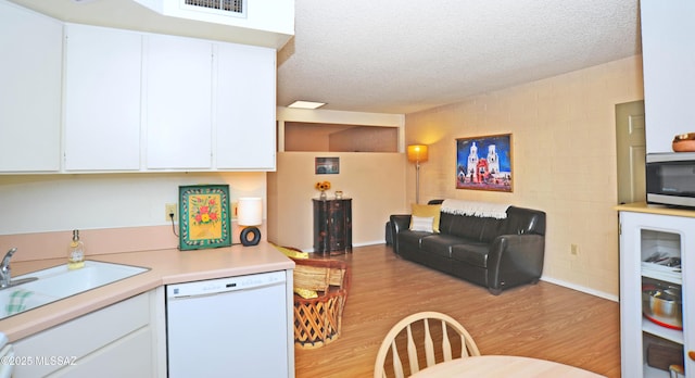 kitchen featuring light hardwood / wood-style floors, white cabinetry, white dishwasher, and a textured ceiling