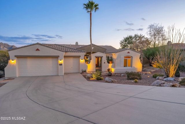 mediterranean / spanish-style house with concrete driveway, stucco siding, a tiled roof, and a garage