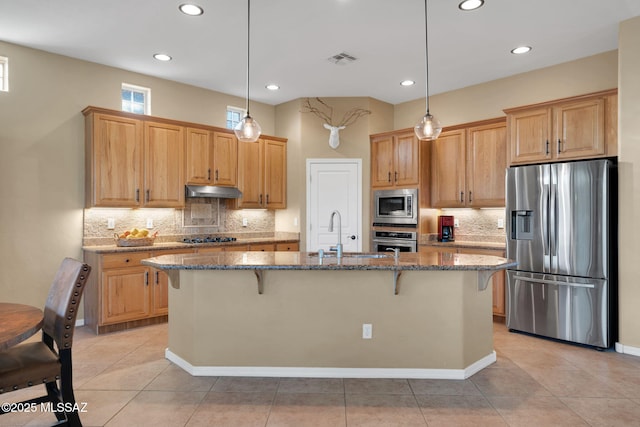 kitchen featuring visible vents, appliances with stainless steel finishes, a kitchen breakfast bar, and stone countertops