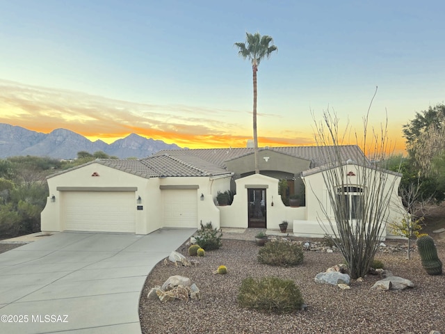 view of front of house with a garage, stucco siding, a tile roof, a mountain view, and concrete driveway
