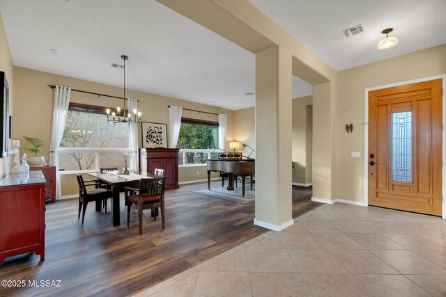 dining space with tile patterned floors, an inviting chandelier, baseboards, and visible vents