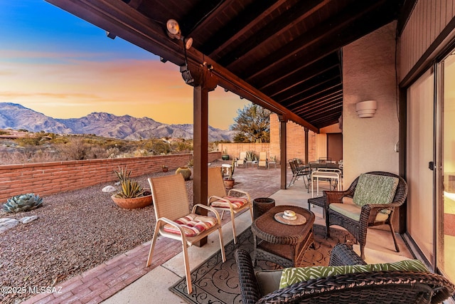 patio terrace at dusk with a mountain view, fence private yard, outdoor lounge area, and outdoor dining space