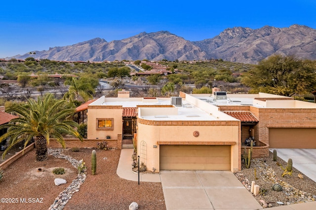 view of front of property featuring central AC unit, fence, stucco siding, concrete driveway, and a mountain view