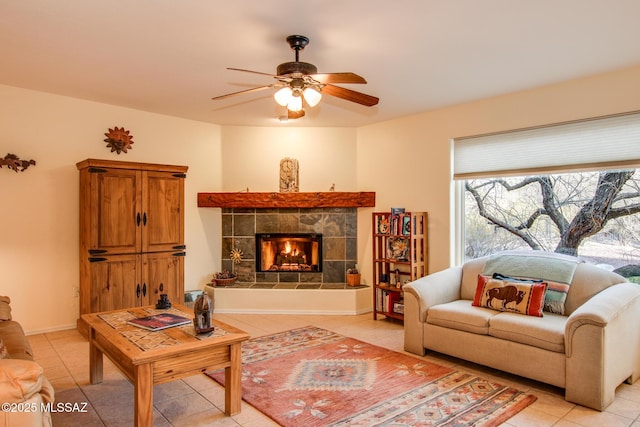 living room featuring light tile patterned floors, a fireplace, and ceiling fan