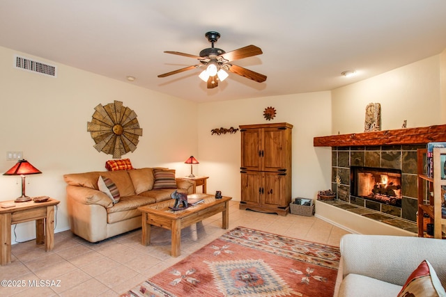 tiled living room with a tile fireplace and ceiling fan