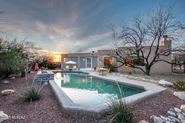 pool at dusk featuring a patio area