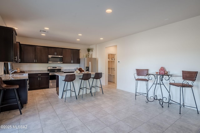 kitchen with stainless steel appliances, a breakfast bar area, and a kitchen island