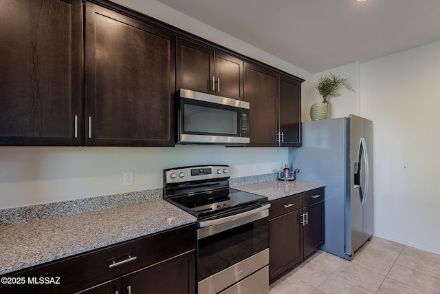 kitchen featuring dark brown cabinets, light stone countertops, and stainless steel appliances