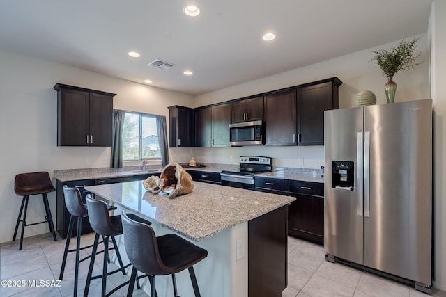 kitchen featuring a breakfast bar area, a kitchen island, dark brown cabinets, and appliances with stainless steel finishes