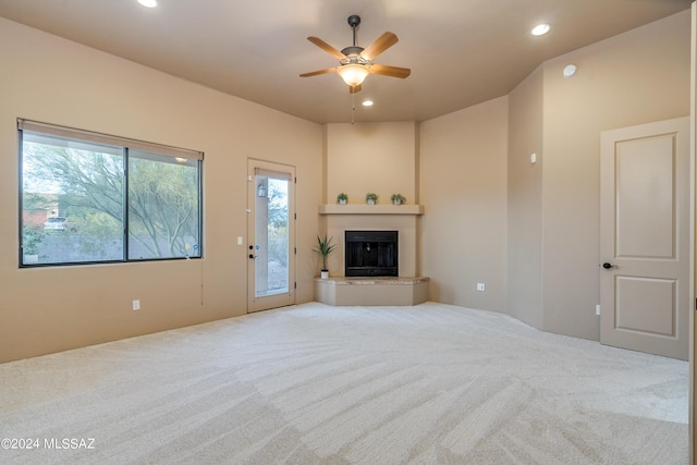 unfurnished living room with ceiling fan and carpet