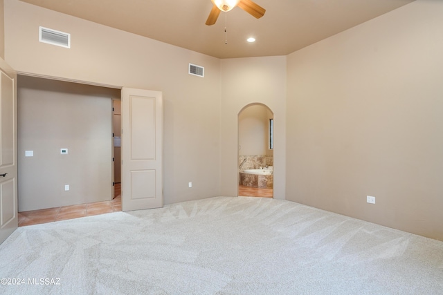 unfurnished bedroom with ceiling fan, connected bathroom, and light carpet