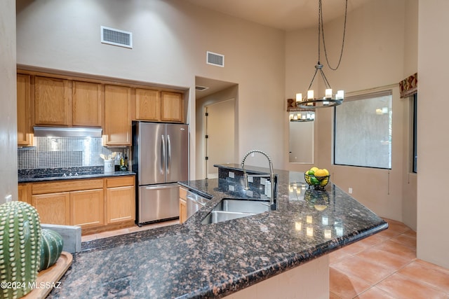 kitchen featuring appliances with stainless steel finishes, decorative light fixtures, dark stone counters, tasteful backsplash, and sink