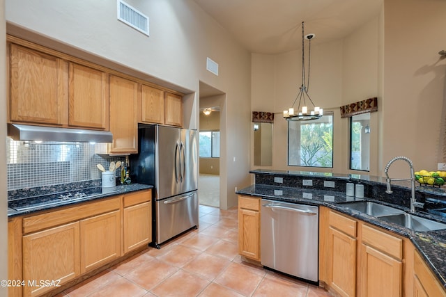 kitchen featuring dark stone counters, hanging light fixtures, sink, a high ceiling, and stainless steel appliances