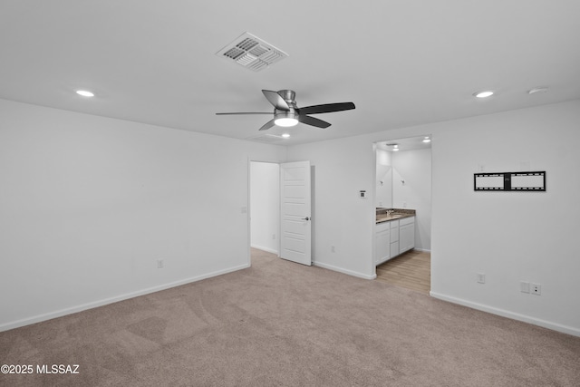 unfurnished bedroom featuring connected bathroom, light colored carpet, and ceiling fan