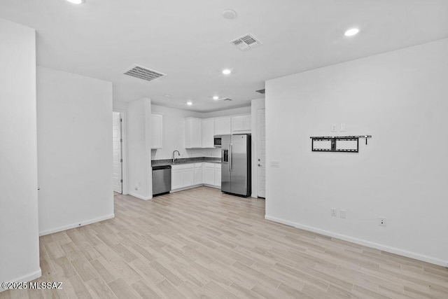 kitchen featuring appliances with stainless steel finishes, sink, white cabinets, and light hardwood / wood-style flooring