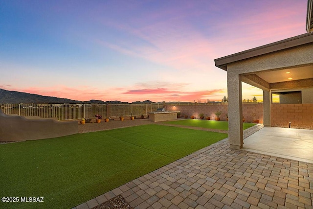 yard at dusk featuring a mountain view and a patio