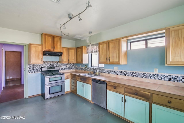 kitchen with tasteful backsplash, appliances with stainless steel finishes, decorative light fixtures, and sink