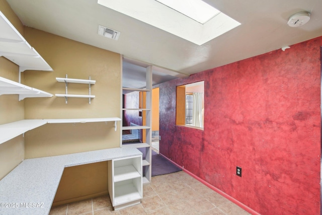 interior space featuring light tile patterned floors and a skylight