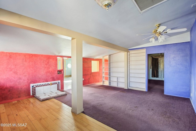 spare room with radiator, built in shelves, vaulted ceiling, and ceiling fan