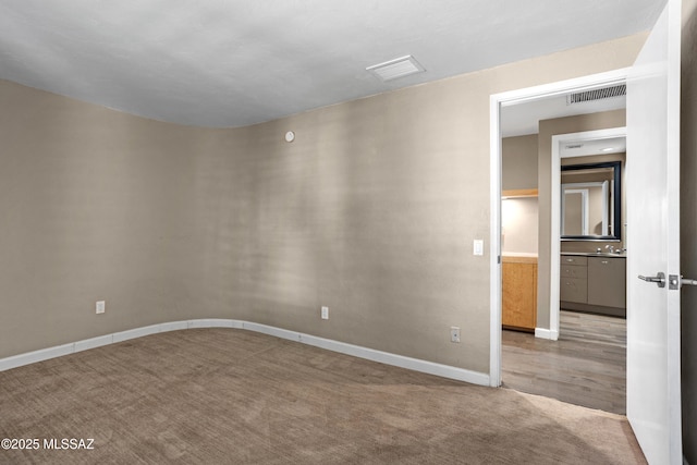 carpeted spare room featuring visible vents and baseboards