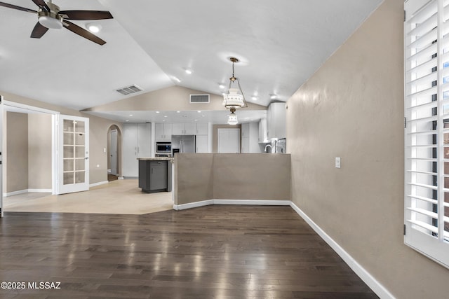 unfurnished living room featuring light wood finished floors, vaulted ceiling, visible vents, and arched walkways