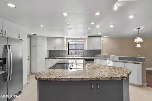 kitchen featuring a center island, backsplash, appliances with stainless steel finishes, white cabinets, and a peninsula