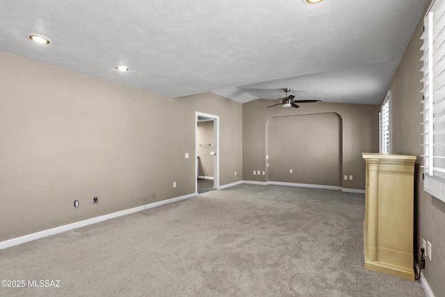 unfurnished living room featuring carpet floors, arched walkways, ceiling fan, and lofted ceiling