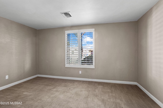 spare room featuring carpet floors, visible vents, and baseboards