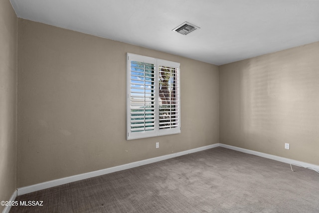 unfurnished room with carpet, visible vents, and baseboards