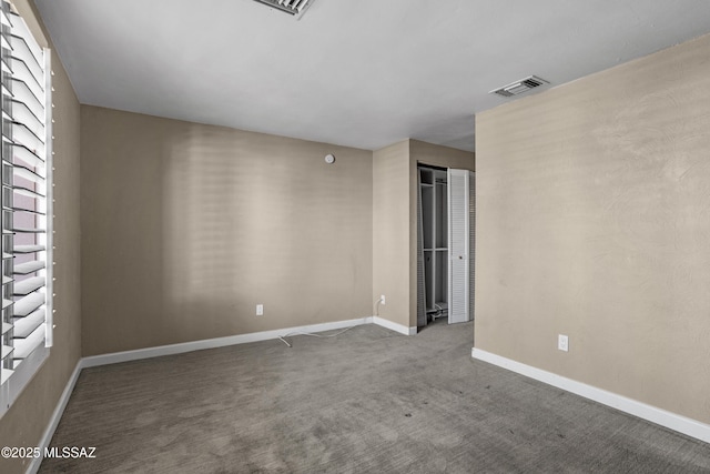 empty room with carpet floors, visible vents, and baseboards