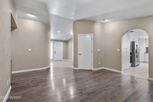 interior space featuring baseboards, visible vents, arched walkways, and wood finished floors