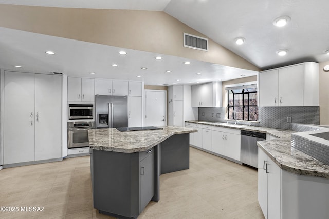 kitchen featuring lofted ceiling, stainless steel appliances, a sink, visible vents, and white cabinetry