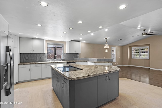 kitchen with a healthy amount of sunlight, a kitchen island, white cabinets, and stainless steel fridge with ice dispenser