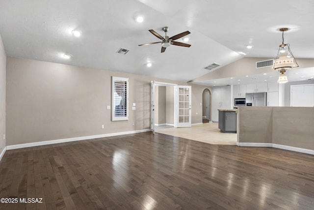 unfurnished living room with lofted ceiling, light wood finished floors, visible vents, and arched walkways