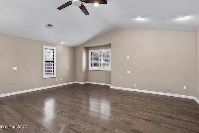 spare room with lofted ceiling, plenty of natural light, visible vents, and dark wood-type flooring