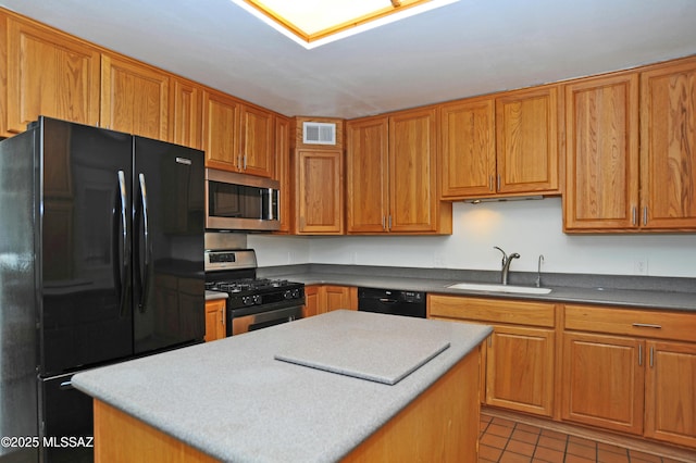 kitchen with sink, light tile patterned floors, black appliances, and a kitchen island