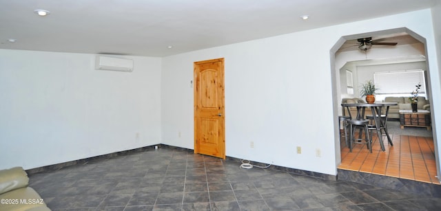 empty room featuring a wall unit AC and ceiling fan