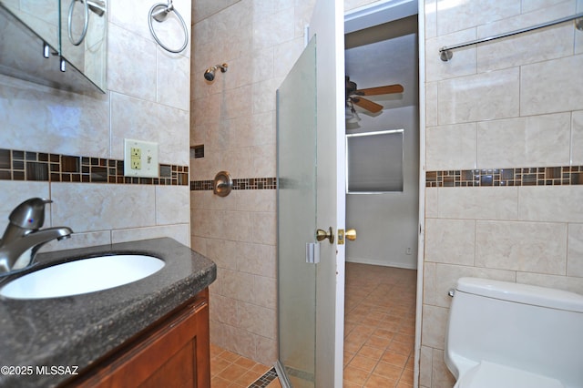 bathroom featuring ceiling fan, tile walls, vanity, tile patterned floors, and toilet