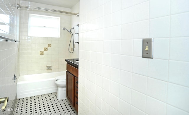 full bathroom featuring vanity, tiled shower / bath, and toilet