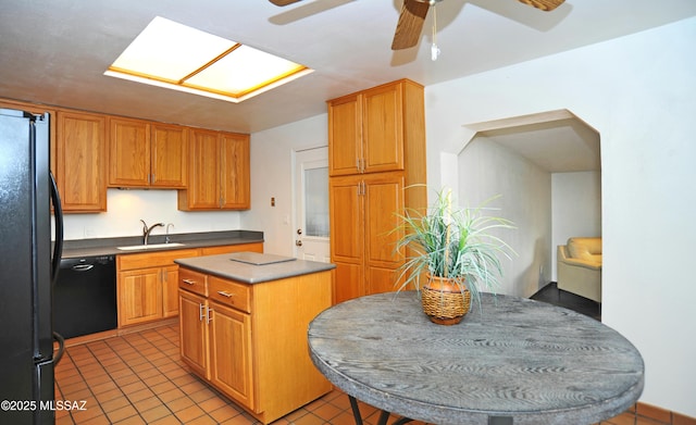 kitchen featuring sink, a center island, light tile patterned floors, ceiling fan, and black appliances